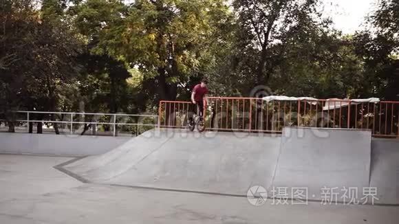 白种人bmx骑自行车的人骑在滑板公园里，骑在坡道上的速度，站在后轮上，然后做轮滑