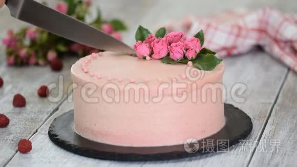 女人切一个用玫瑰装饰的漂亮蛋糕。 甜食。