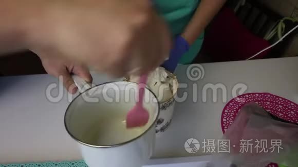 一个人在容器里加入炖锅糖浆。 女人用搅拌机把棉花糖和糖浆混合在容器里