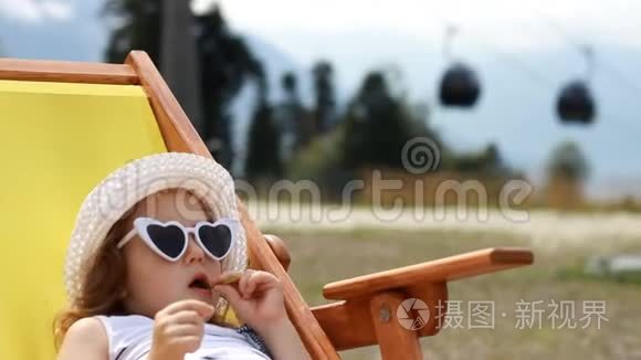 旅游女婴坐在缆车附近的躺椅上。 滑雪电梯的电缆方式，供人们运输