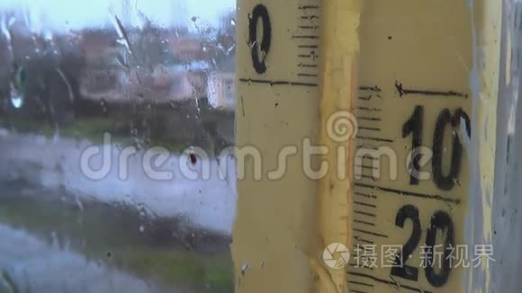 外面下雨的天气。 窗户玻璃上的水滴，雾状温度计刻度