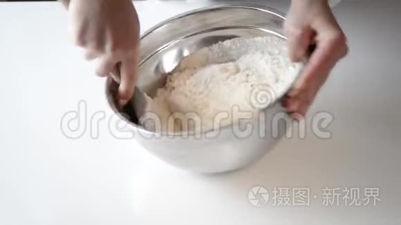 女人混合配料做饼干。 面包师用鸡蛋、糖和面粉在白色桌子上的碗里准备面团。