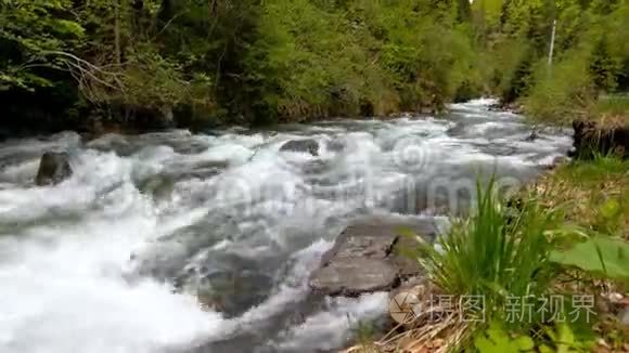 阳光明媚的一天，湍急的山河在巨石之间流淌。