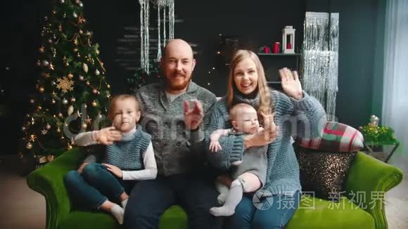 圣诞概念-幸福的一家人坐在沙发上挥手致意