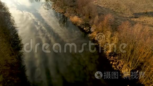 一架四翼飞机沿着一条被干燥的黄色植被包围的春河飞行，空中视频