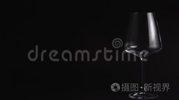 侍者把红酒倒进一个漂亮的空杯子里。在酒吧或餐馆品酒。孤立，黑色