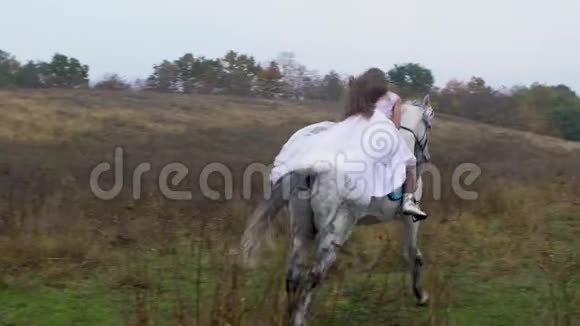 身穿婚纱的长发女子骑着奔腾的骏马穿过山谷视频的预览图