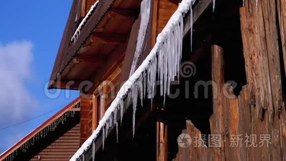冰柱融化并滴在太阳上悬挂在木屋的屋顶上。 慢动作