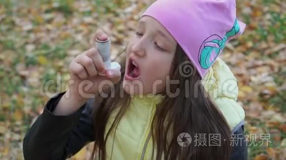 一个戴着帽子和夹克的女孩在秋林散步时以吸入剂的形式吃药治疗支气管哮喘。 流感