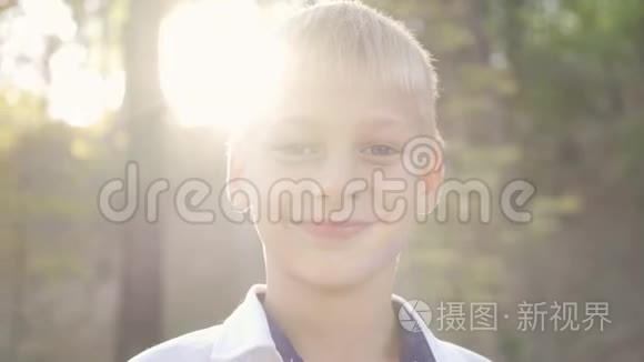 特写一个可爱的男孩看着相机微笑。 公园里一个孩子在阳光下的肖像。 休闲活动