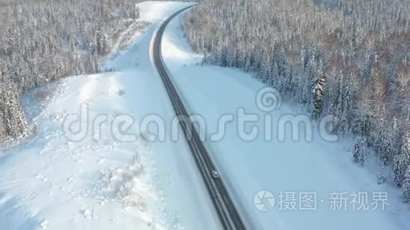 公路穿越冬林，航拍.. 在高速公路上行驶汽车。 树上的雪