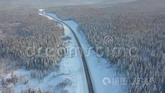 公路穿越冬林，航拍无人机.. 在高速公路上行驶汽车。 树上的雪