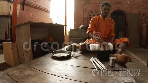 穿着橙色衣服的年轻印度僧人用棉花做蜱虫夜礼