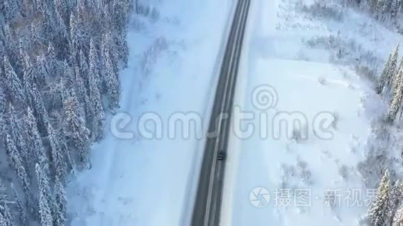 公路穿越冬林，航拍无人机.. 在高速公路上行驶汽车。 树上的雪