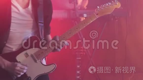 穿黑色衬衫的吉他手在舞台上用手指弹奏电吉他