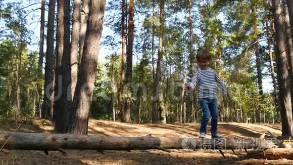 快乐的孩子花时间在公园或森林的户外玩耍。 活跃的男孩正走在横梁上克服障碍
