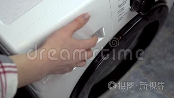 一个年轻的女人把洗涤剂倒进洗衣机里。 一个女人把粉末和液体倒入一个特殊的隔间