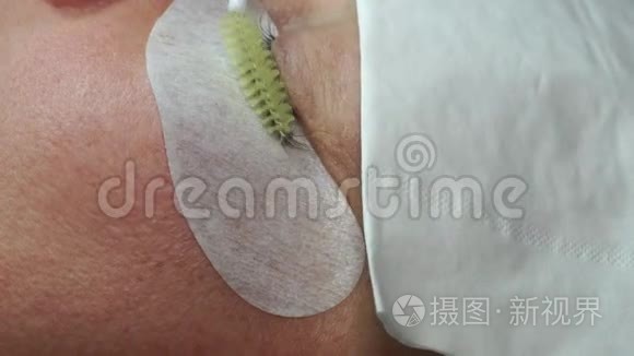 用镊子粘合人造睫毛。 化妆程序。 睫毛延伸。 女人的眼睛长着睫毛