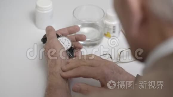 老人在白桌旁检查脉搏和手表视频