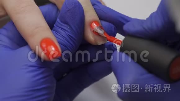 特写专业美容师美甲大师打磨指甲.. 女人正在修指甲。 用红色盖住指甲