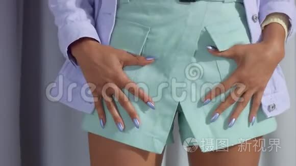 不可辨认的女人穿着淡紫色的金属指甲，双手插在口袋里
