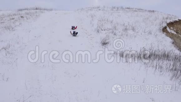 圣诞节期间，快乐的孩子们在冬天的公园里从雪山上滑过雪橇。 慢动作