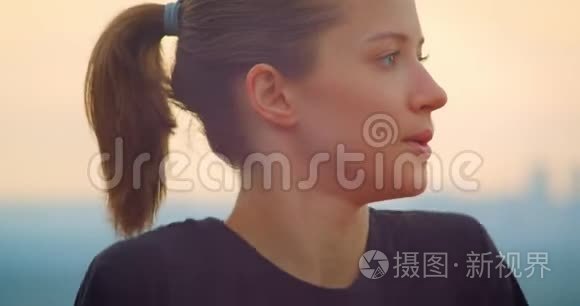 年轻的运动型女慢跑者穿着黑色t恤，在户外看美丽的日落