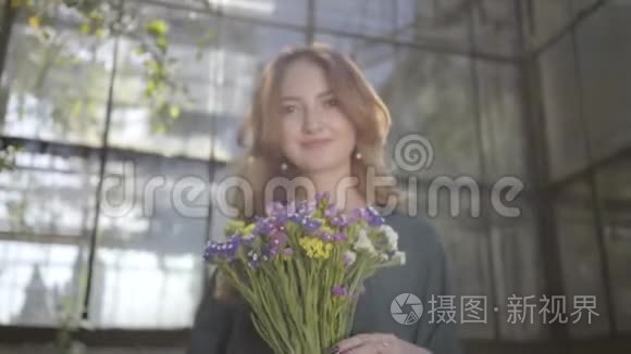 一幅美丽的年轻女子拿着一束野花站在老楼里看镜头的肖像。 概念