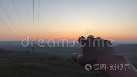 日落天空背景下男性手的特写。