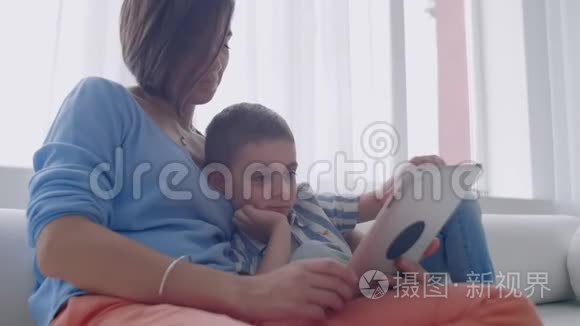 母子俩在家玩数字平板电脑.. 年轻的母亲带着她5岁的孩子带着数码平板电脑微笑