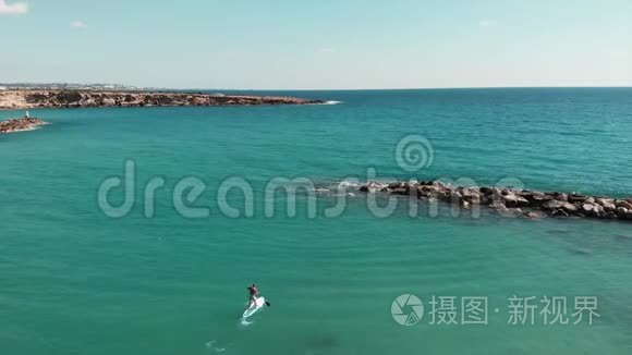 鸟瞰蓝色晶莹剔透的海水.. 无人机拍摄美丽的岩石海岸线。 年轻有魅力的男人在他身边