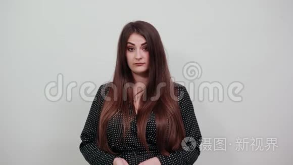 一位严肃的年轻白种人女士用手指指着隔离的灰色墙壁