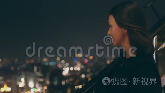 美丽的女人看着夜晚城市屋顶视频