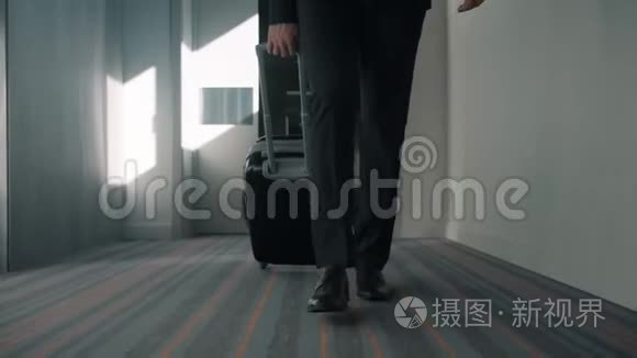 商务男士双腿带旅行箱，走在酒店走廊