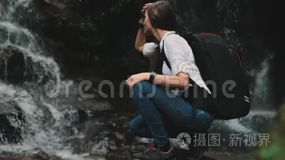 女旅行者蹲在飞溅瀑布附近视频