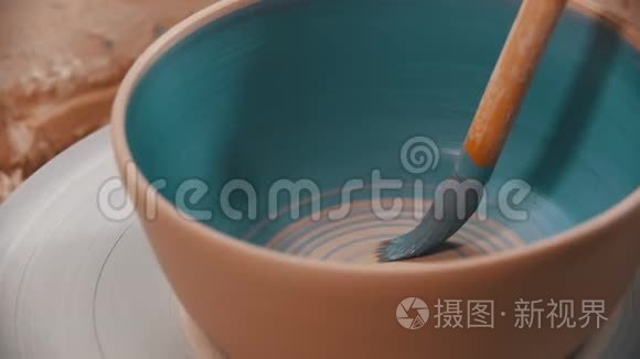 陶工正在陶轮上用蓝色在里面画一个陶碗