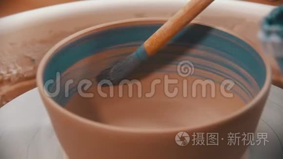 陶工正在用蓝色的画笔在陶轮上画一个陶碗