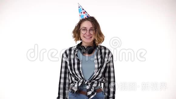 兴奋的年轻女子穿着格子衬衫，戴着耳机，戴着生日礼物，戴着五颜六色的帽子，吹着烟斗，飘落下来