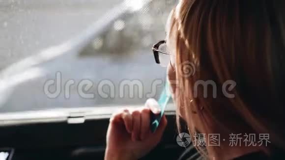 当汽车开动时，那个女孩沉思地看着窗外。 她拿着一张塑料卡片