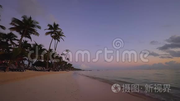 日出覆盖热带岛屿海滩和棕榈树。 多米尼加蓬塔卡纳