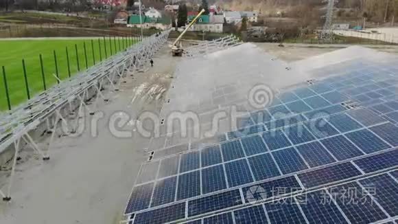 在太阳能电池板发电厂上空飞行。 工人安装太阳能电池板，并将为工厂供电