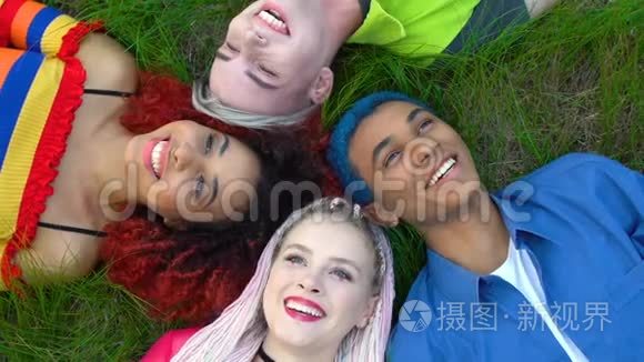 快乐的多种族女性和男性潮人躺在草地上欢笑，朋友