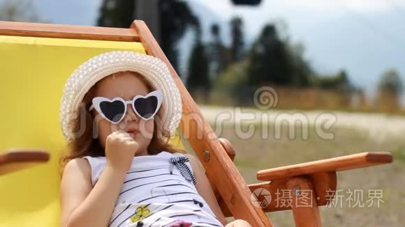 旅游女婴坐在缆车附近的躺椅上。 滑雪电梯的电缆方式，供人们运输
