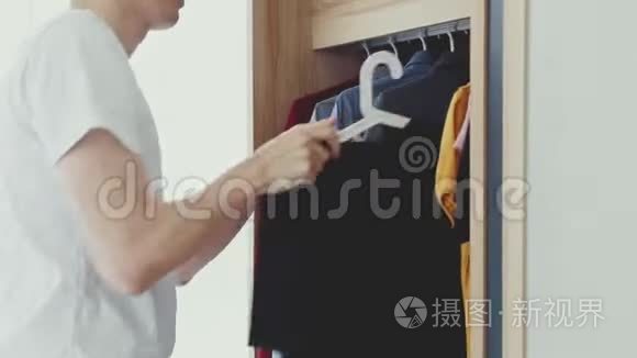 男人从衣柜里拿起一件黑色T恤。