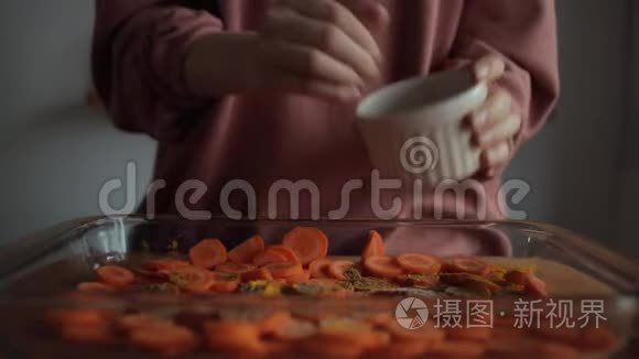 一个年轻女人的手在厨房里放了一盘切碎的胡萝卜。 特写