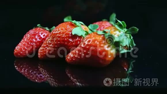 特写镜头集中在一组新鲜多汁的红色草莓上，放在黑色上