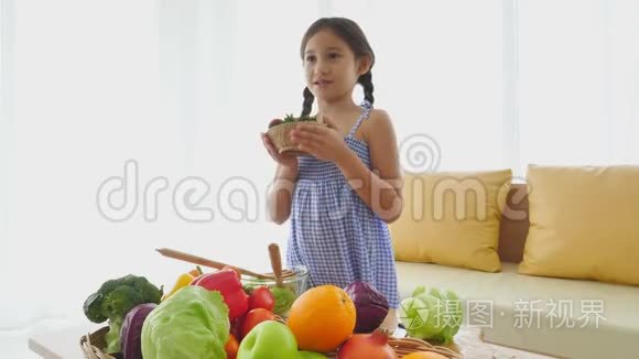 可爱的女孩用混合水果和蔬菜做沙拉，并在客厅里向客人介绍。 家庭和人民幸福