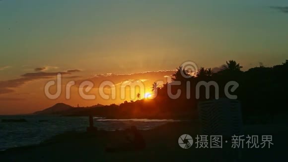 夕阳红下的全景，在海岸的棕榈树的映衬下