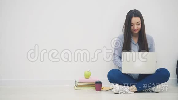 年轻的亚洲女学生坐在洛托斯的位置上，用手提电脑，用手指举起来，就好像在拿着一个