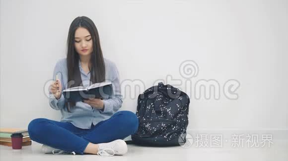 灵感来自年轻的亚洲女孩坐在地板上，写完字，从背包里拿出手机和耳机，然后